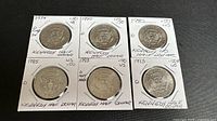 Photo of six Kennedy half dollar coins dated 1974, 1980, 1983, 1990, 1993 with mint marks D and P in protective holders.