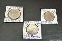 Three silver dollar coins secured in cardboard holders with handwritten labels showing dates and names: 1873-1973 Prince Edward Island Centennial, 1867-1982 Confederation Constitution, and 1984 Jacques Cartier.