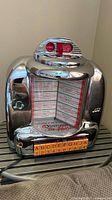 Front view of chrome Venturer Crowley Select-O-Matic novelty jukebox radio with coin slot and orange selector buttons