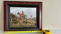 Frontal view of framed painting and visible tape measure
