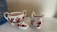 Three-piece miniature Coalport Indian Tree fine china set with sugar bowl (with lid) and creamer in red floral design with gold accents