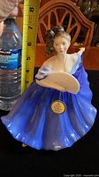 Front view of Royal Doulton Elaine figurine with measuring tape showing approx 7.3-7.4 inch height and a water bottle for scale