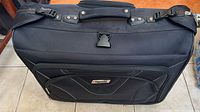 Closed black Tracker garment luggage showing handle and front pocket