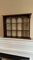Full front view of wooden 3-tier wall display shelf with arch design and spindle columns.