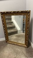 Full front view of the mirror showing the gold ornate frame and reflective glass.