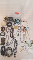 Photo of a collection of various costume jewelry items laid out including necklaces, rings, bangles, bracelets, and pins in earth tones and metallics.