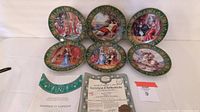 Six Limoges decorative plates arranged on a white backdrop showing various historical and classical scenes with green borders. Certificate and stand partially visible in the image.