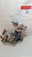 Front and side angle of porcelain figurine showing boy crouched with puppies and dog.