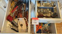 Top-level view of two open drawers showing flatware and plastic bins of utensils