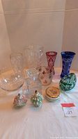 Lot contents showing crystal vases, bowls, green cut dish, porcelain figurines, and trinket box arranged on table.