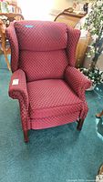 Front view of red upholstered reclining armchair with cross-hatched diamond pattern fabric, showing padded headrest and armrests.