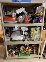 Full view of three plastic shelves stacked with assorted kitchenware, bakeware, vases, and decorative items
