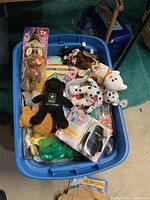 Blue plastic tub filled with multiple Beanie Babies plush toys, some with Ty tags and packaging, various animals visible