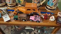 Wooden vintage-style car, two metal cars (green and pink), bird figurines, key chain on wooden shelf