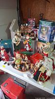 Full view of table with assorted Santa figures in various poses and miniature Christmas decorations including village and tree.