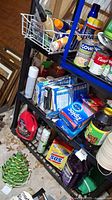Photo of cleaning supply shelves showing cleaning wipes, spray bottles, boxes of pads, and canned foods
