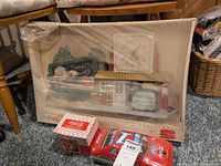 Photo showing Coca-Cola clock in packaging, 1940s-1950s mug, and red Coca-Cola race car tin at floor level.