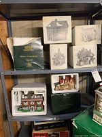 Shelved collection of seven houses from the Dickens Village Series, mostly in original boxes with packaging.