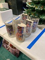 Six Disney 25th Anniversary collectible glasses grouped together on a table, showing colorful Disney character graphics on clear glass.