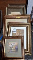 Seven framed floral prints stacked, showing gold-tone frames and some mat borders.