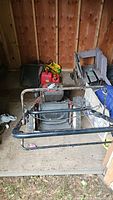 Craftsman lawn mower with engine, black metal handlebar, and grass catcher bag in barn/shed