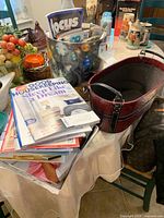 Photo showing the leather look basket, metal canister, and a pile of magazines and books on a table.