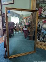 Full view of rectangular mirror with gilded frame showing reflection of room.