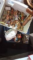 Photo of assorted nativity figurines inside a box along with other religious figures and the wooden crucifix laying on top.