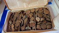 View of mixed pennies in a divided box showing many Lincoln wheat pennies with varying ages and dirt, highlighting the condition requiring cleaning.