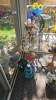 Full view of the corner display including metal plant stand, frog decor, dream catchers, glass vase with sunflowers, candle holder, and water pitcher