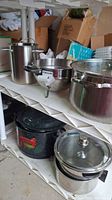 View of assorted pots including stainless steel pots and enamel pot