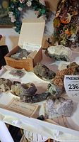 Photo showing assortment of rocks and mineral specimens, some labeled and placed on a table with handwritten notes.