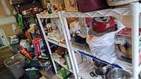 Wide angle view showing 3 white plastic shelving units with stored items, dusty and cluttered.