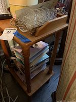 Wood side table shown with items on top and magazines on the bottom shelf.