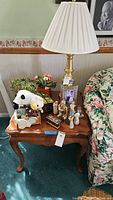 Wooden side table shown with various decorative items on top including a lamp and figurines, to showcase surface and style of table; items not for sale.