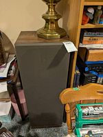 View of one Sansui speaker showing wood veneer top and gray fabric front speaker grille with brass lamp on top
