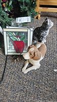 Photo of two stained glass frames, plastic dog and cat figurines on carpeted floor
