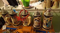 Full view of set of 5 20th Century in Review Anheuser beer steins and original wooden display stand.