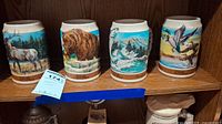 All four ceramic steins with wildlife scenes displayed on a shelf.