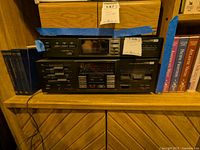 Front view of the stacked Sansui stereo equipment on a wood shelf with books surrounding it.