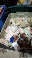 Photo of a plastic tote filled with assorted stuffed animals including sheep, pig, and other plush toys.