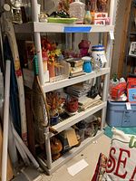 Three shelves filled with various decor items including vases, books, glass bottles, a fishing net, and enamelware pot. Items are dusty and need cleaning.