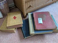 Top view of the pile of vintage books including two large gold-covered Webster's Universal Unabridged Dictionary volumes and other vintage books in different colors.