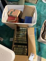 White plastic bin containing assorted vintage books with various bindings and colors.