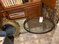Three vintage mirrors and frames arranged on the floor: intricate gold ornate round mirror, simple square mirror, and oval glass tray frame with handles.