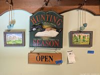 Photo showing the overall wooden hunting season wall hanging with duck illustration and two framed watercolor prints on either side