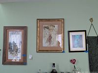 Photo of three framed signed prints under glass displayed on a wall, varying in size and framing style