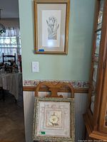 Two framed floral prints leaning against wall under a mounted floral print.