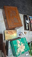 View of hand carved wooden box, two music boxes and angel figurine on concrete floor