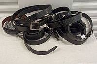 Lot image showing 10 black men's belts arranged on a white surface, belts coiled and stacked with visible buckle details.